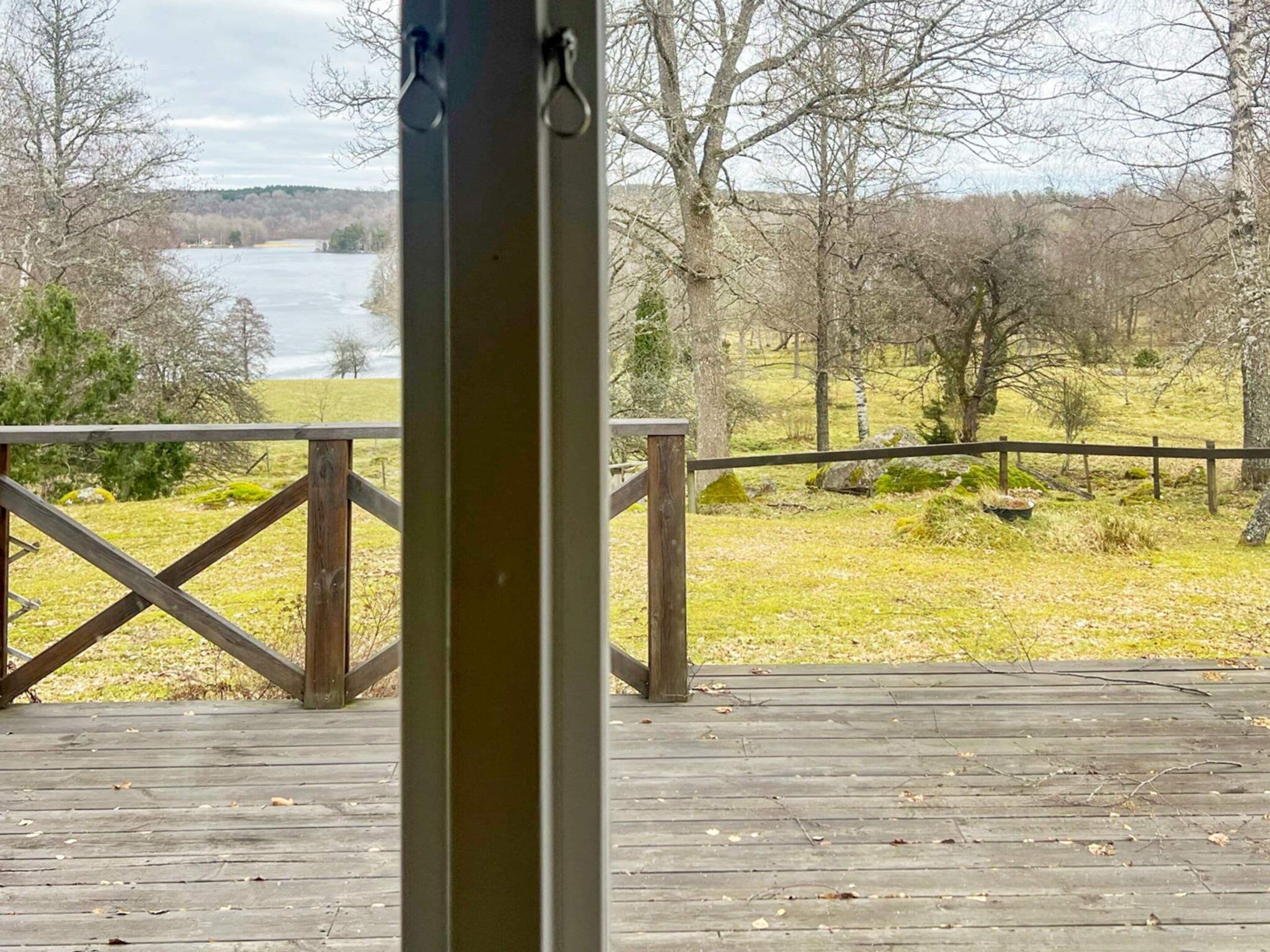 A wooden deck with a railing overlooking a river and trees.
