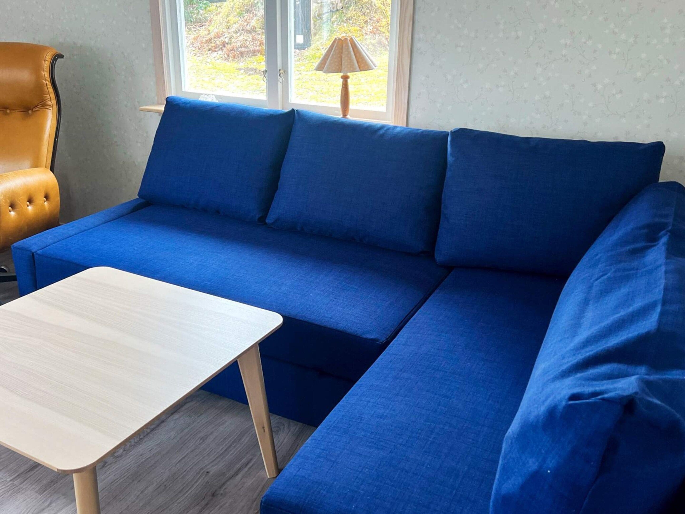 A blue sofa with a matching armchair and a small wooden table in a room with a window.