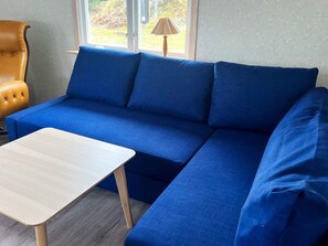 Un canapé bleu, accompagné d’un fauteuil assorti et d’une petite table en bois, dans une pièce dotée d ’une fenêtre.