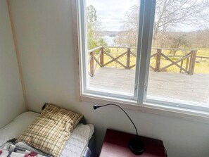 Une chambre avec un lit, une fenêtre et une vue sur une terrasse en bois et une rivière.