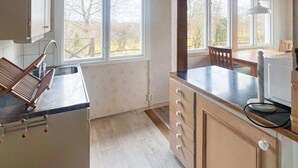 Une cuisine dotée d’une grande fenêtre, d’un plan de travail en bois et d’un four encastré.