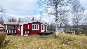 Un bâtiment rouge avec un porche, une cheminée et une petite terrasse.