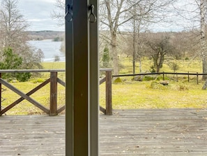 A wooden deck with a railing overlooking a river and trees.