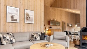 A cozy living room with a sofa, two round wooden tables, and a fireplace. - 4 Star Holiday Home in Albaek (Aalbaek)