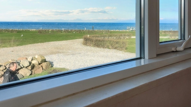A view from a window overlooking a grassy area with a body of water in the distance. - 4 Person Holiday Home in Bogense (Bogense)