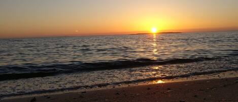 A beach with the sun setting over the ocean, creating a calm and serene atmosphere.