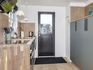A modern kitchen with a black door, wooden countertops, and pendant lights. - 4 Star Holiday Home in Logstor (Logstor)