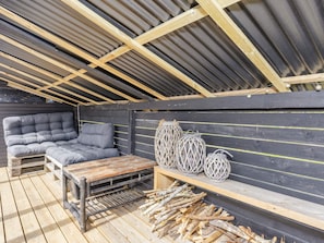 An outdoor seating area with a wooden bench, a cushioned sofa, and decorative lanterns. - 4 Star Holiday Home in Logstor (Logstor)