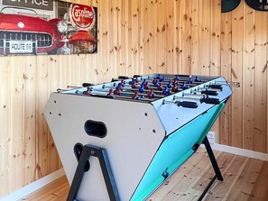 A foosball table in a room with wooden walls and a vintage car poster. - 4 Star Holiday Home in Logstor (Logstor)