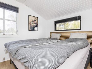 A bedroom with a bed, a window, and a wall-mounted picture.