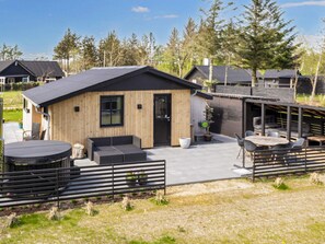 A modern house with a wooden exterior, a black roof, and a patio area with outdoor seating. - 4 Star Holiday Home in Logstor (Logstor)
