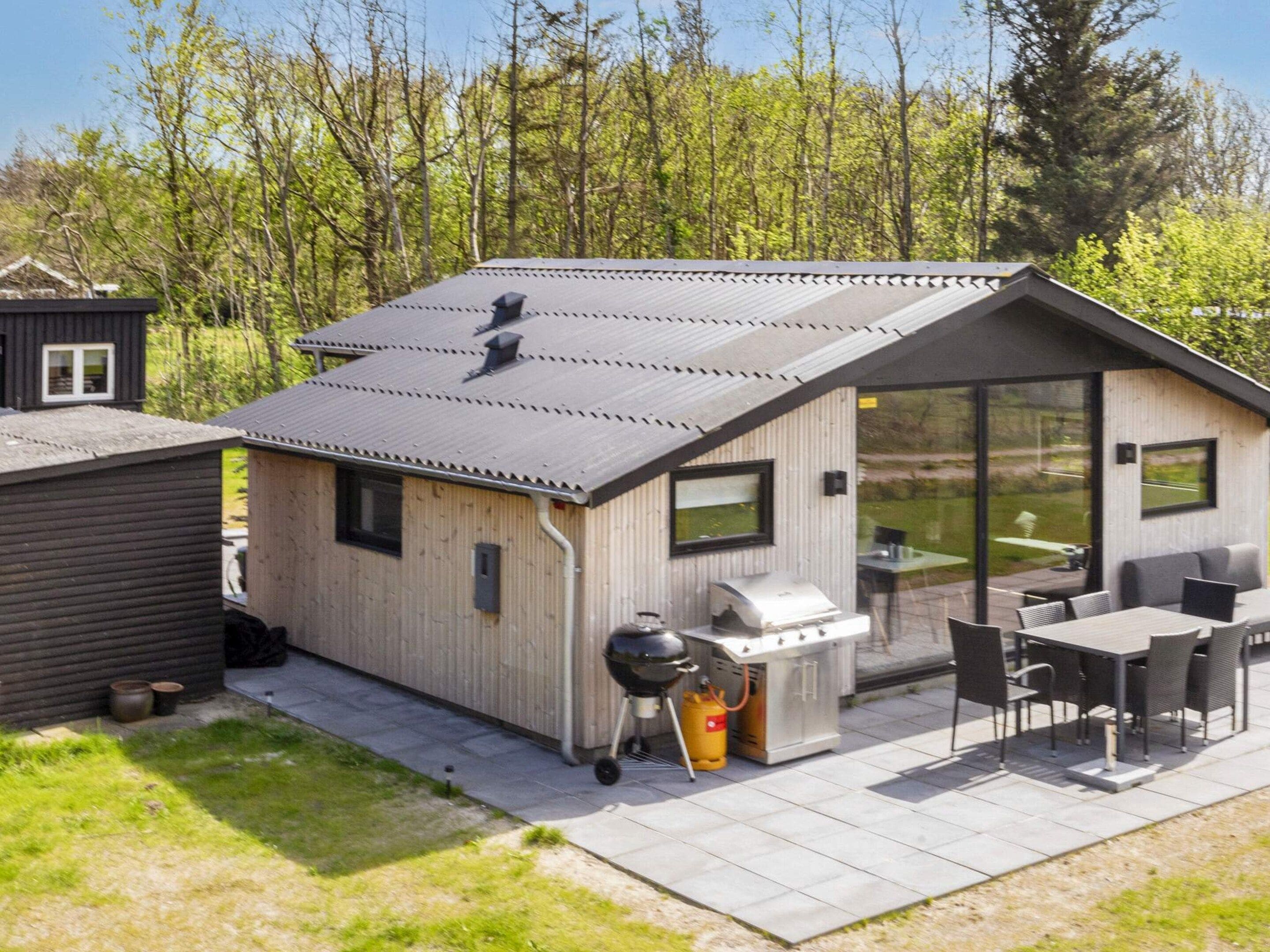 A modern outdoor kitchen with a grill, a table, and chairs.