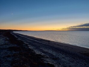 Una playa con cielo despejado y una luna creciente.