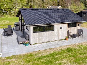 A modern outdoor kitchen with a grill, dining area, and seating. - 4 Star Holiday Home in Logstor (Logstor)