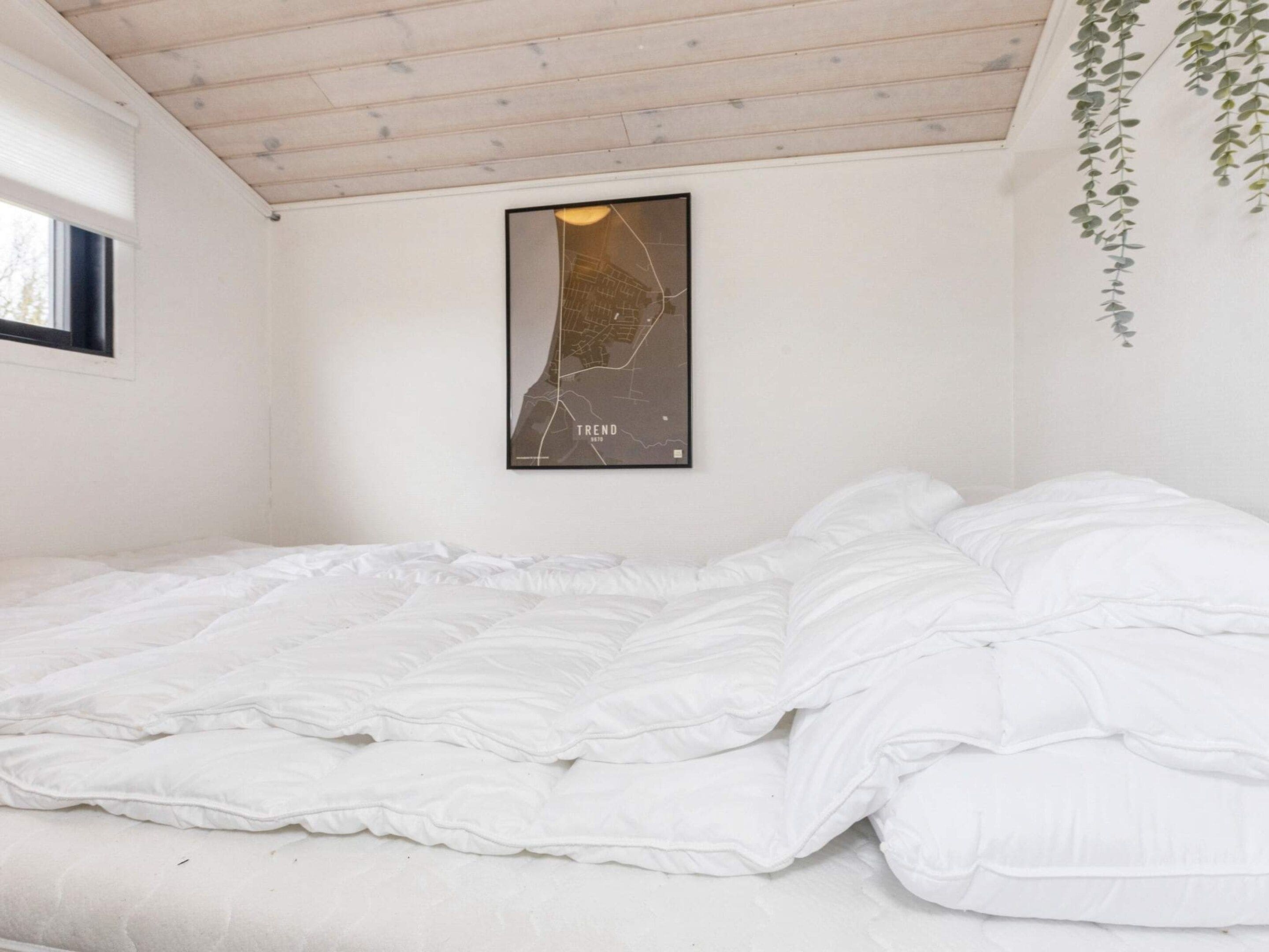 A bedroom with a bed, a map on the wall, and a window.