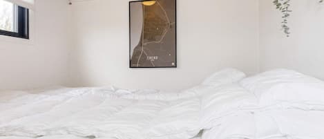 Une chambre à coucher avec un lit, une carte accrochée au mur et une fenêtre.