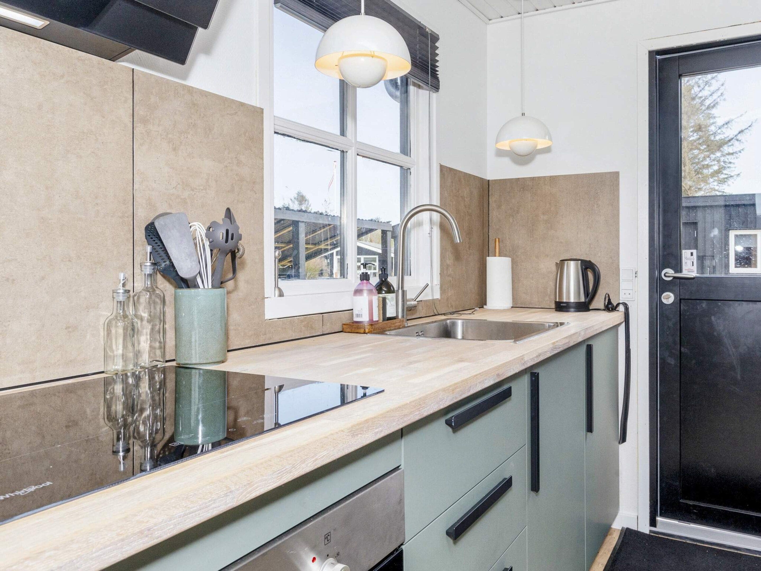 A modern kitchen with a large window, a sink, and a door.
