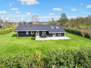 A modern house with a large front yard, a patio with outdoor furniture, and a garage. - 4 Star Holiday Home in Orsted (Ørsted)