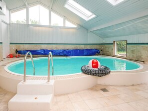 Piscina interna com trampolim, boia salva-vidas e cobertura.