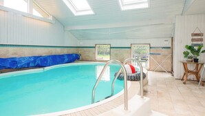 Una piscina interior con agua cristalina azul, una cubierta azul y un puesto de socorrista.