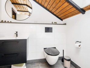A modern bathroom with a white sink, black cabinet, white toilet, and a mirror above the sink. - 5 Person Holiday Home in Toftlund (Toftlund)