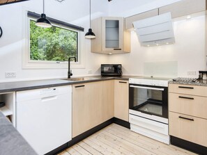 A modern kitchen with a dishwasher, microwave, oven, and a window with a view of greenery. - 5 Person Holiday Home in Toftlund (Toftlund)