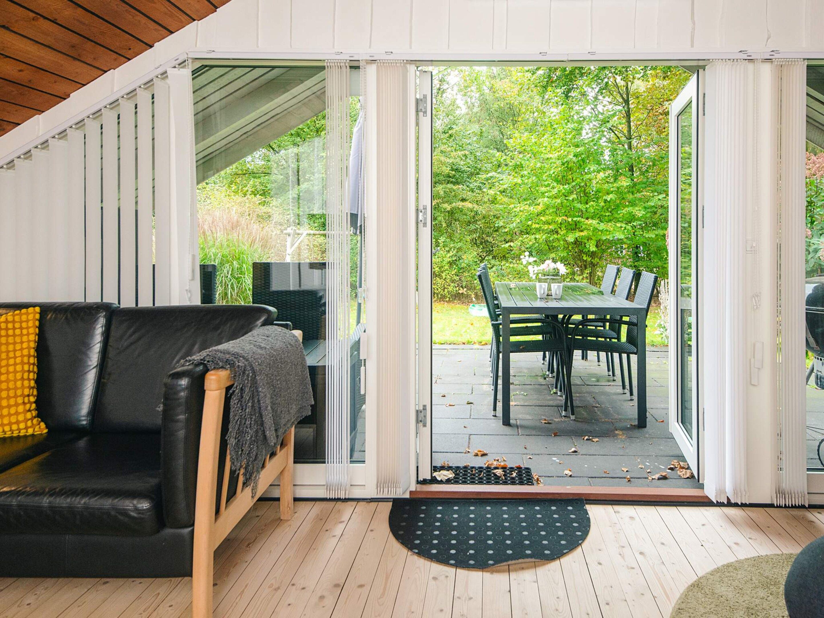An open sliding door leading to an outdoor patio with a dining table and chairs.