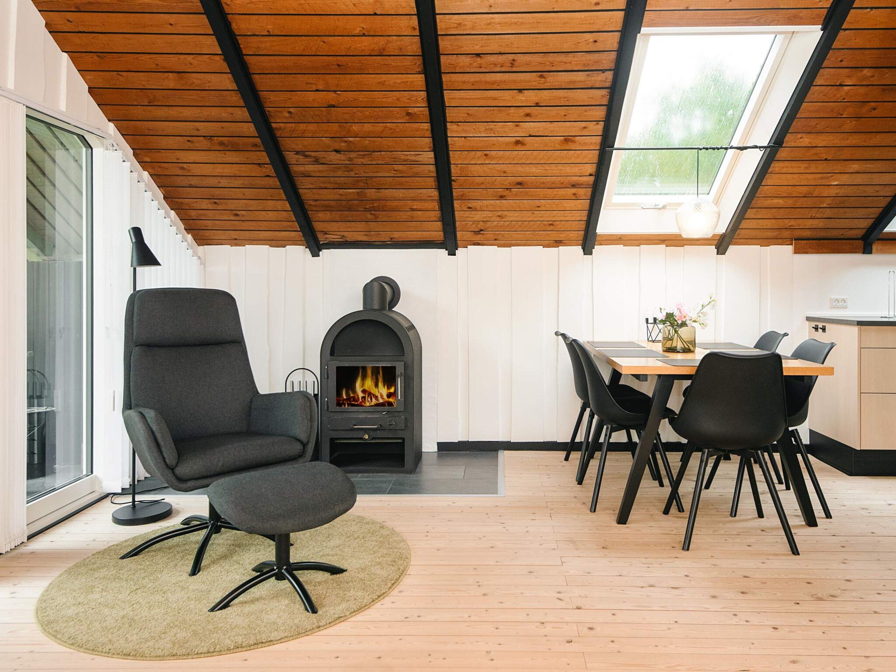 A modern interior with a fireplace, a dining area, and a skylight.