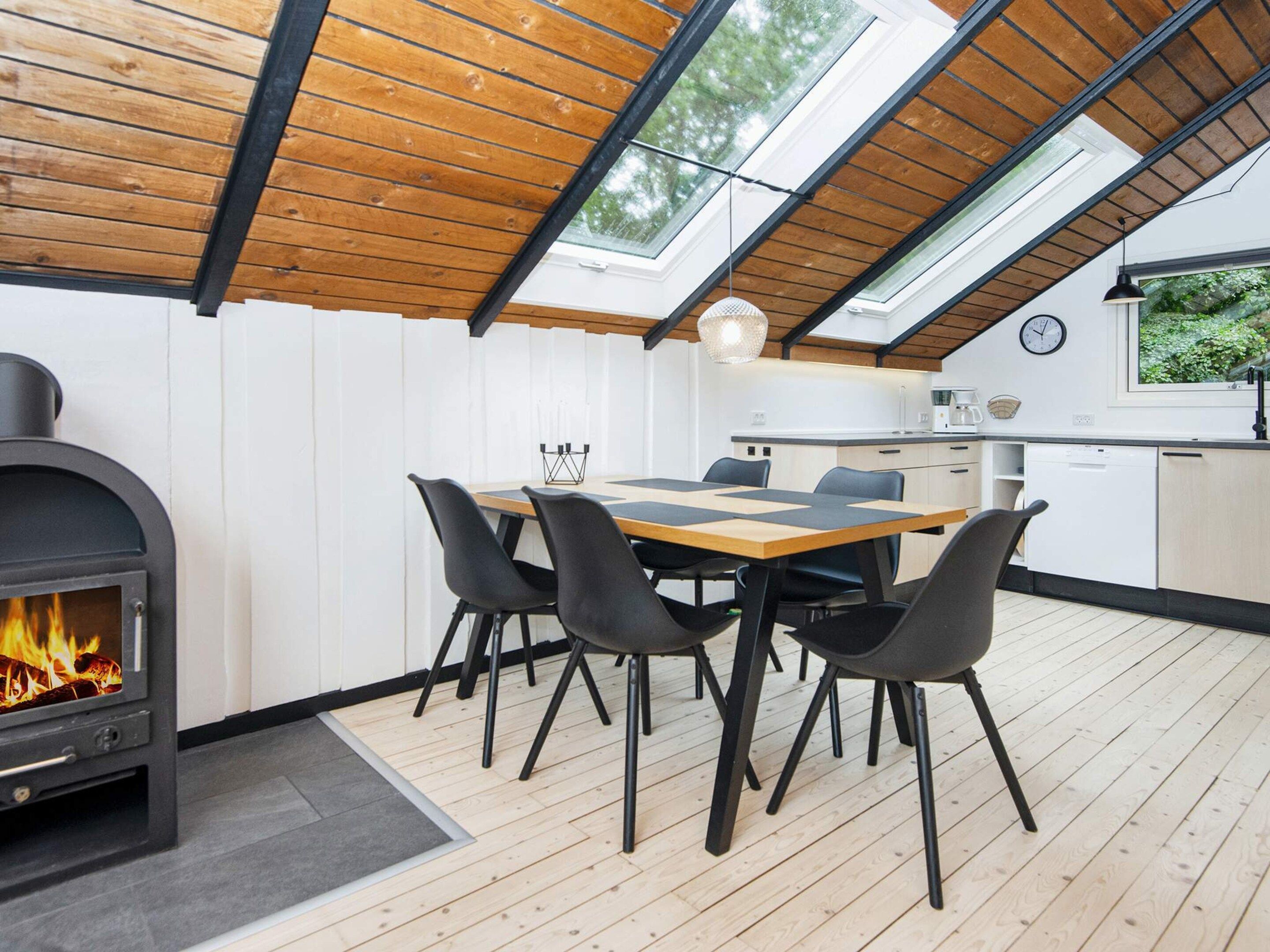 Una cocina moderna con comedor, tragaluces y estufa de leña.