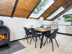 A modern kitchen with a dining area, skylights, and a wood-burning stove. - 5 Person Holiday Home in Toftlund (Toftlund)