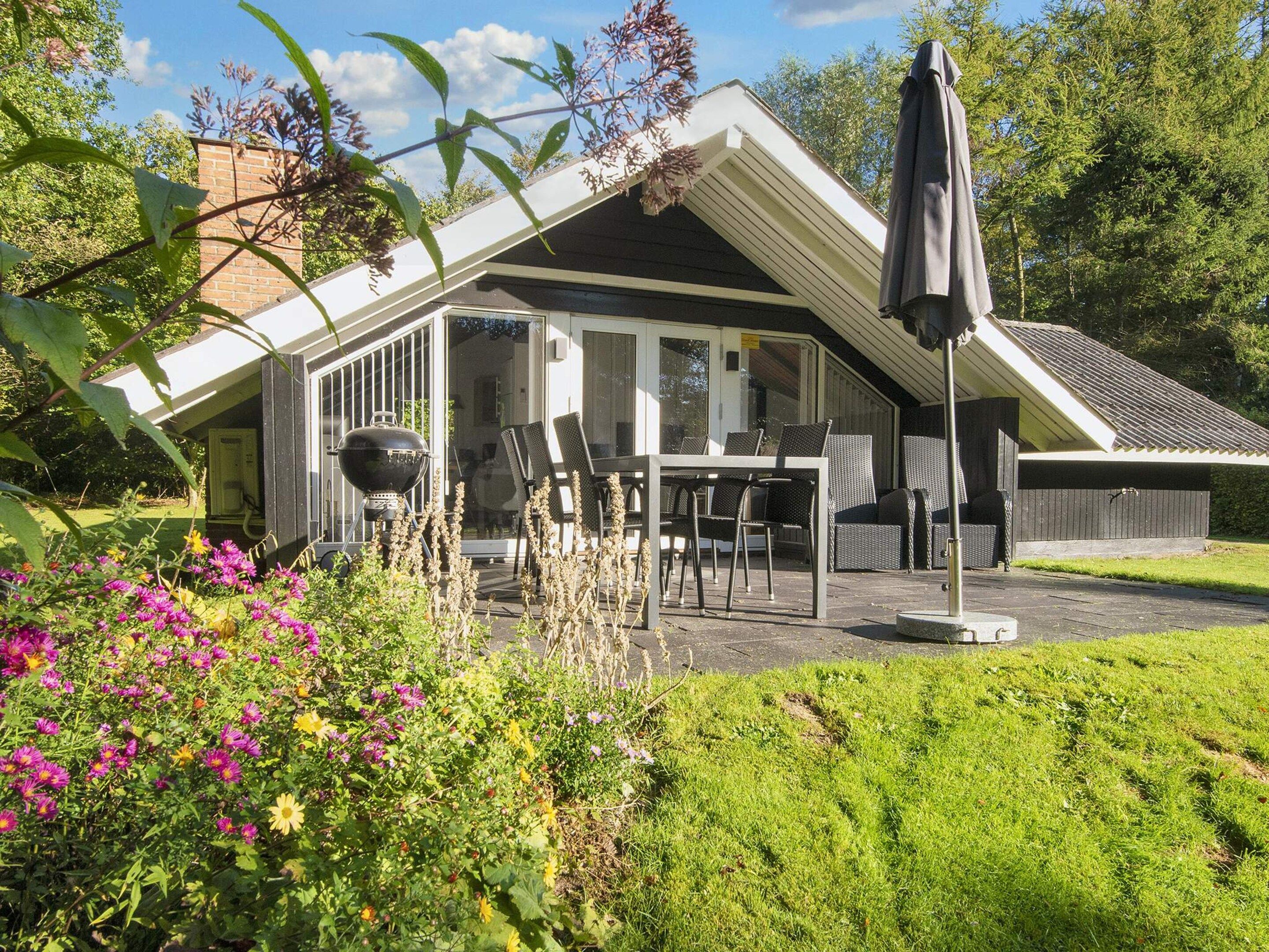 Un espace extérieur abrité, avec une table et des chaises, un barbecue et un parasol.