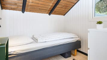 Un dormitorio compacto con una cama individual, un escritorio pequeño y una ventana con vistas a zonas verdes.