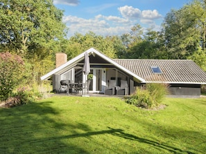 A house with a sloped roof, a covered patio with outdoor furniture, and a large window.