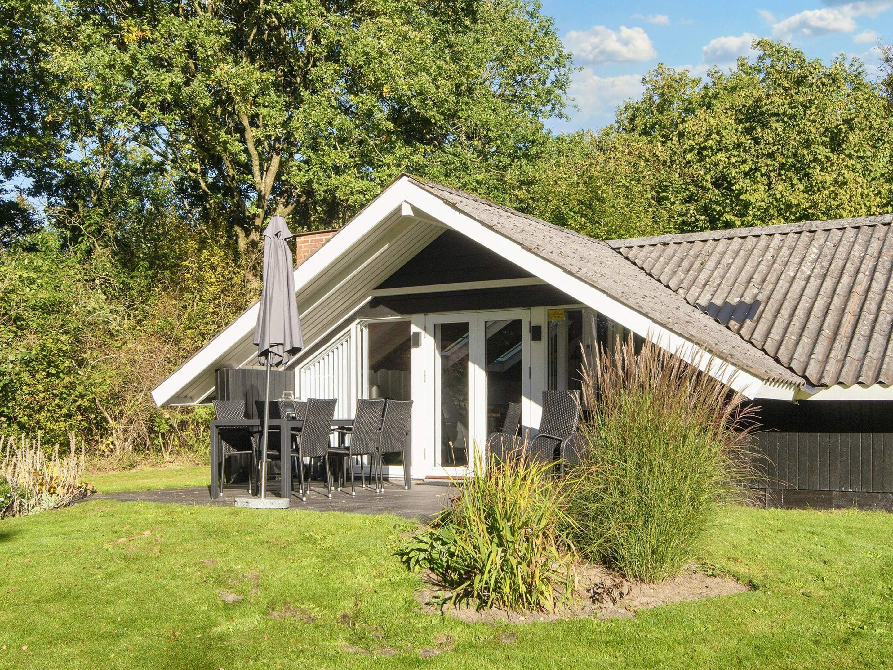 Ett hus med en uteplats, utomhusmöbler och en delvis takförsedd yta.