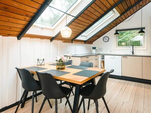 A dining area with a wooden table, black chairs, and a vase of flowers. - 5 Person Holiday Home in Toftlund (Toftlund)