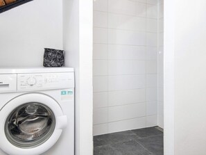 A compact laundry room with a front-loading washing machine and a tiled wall. - 5 Person Holiday Home in Toftlund (Toftlund)