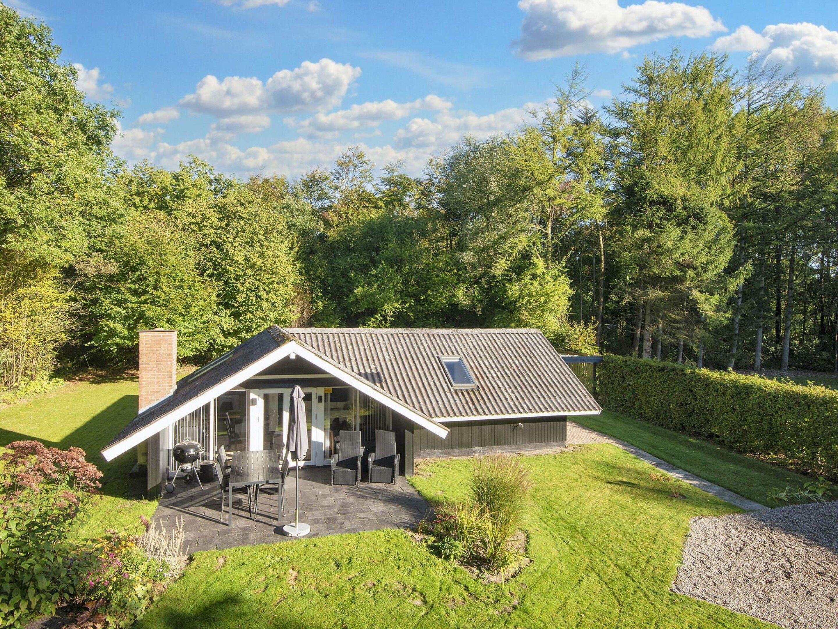 Uma casa moderna com telhado inclinado, um pátio com mobiliário para área externa e um jardim bem cuidado.