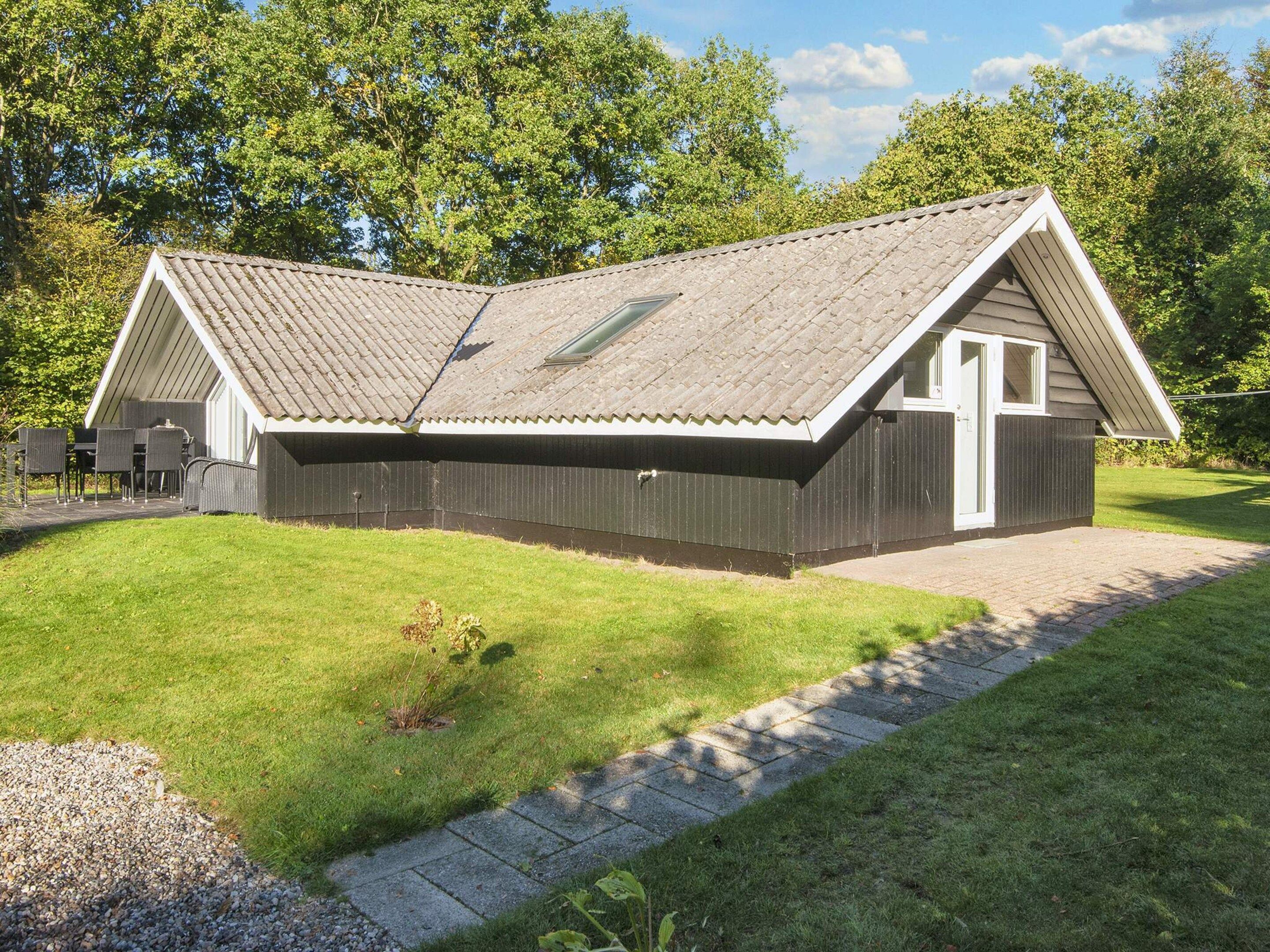 A single-story building with a sloped roof, a small porch, and a paved driveway.