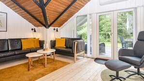 A modern interior with a wooden ceiling, a sofa set, a round table, and a view through glass doors to an outdoor area. - 5 Person Holiday Home in Toftlund (Toftlund)