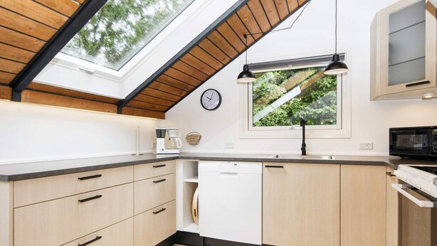 A modern kitchen with a skylight, wooden cabinets, a dishwasher, and a microwave. - 5 Person Holiday Home in Toftlund (Toftlund)