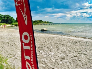 Una playa con un cartel rojo que dice "OTTO GLASSFABRIKEN".