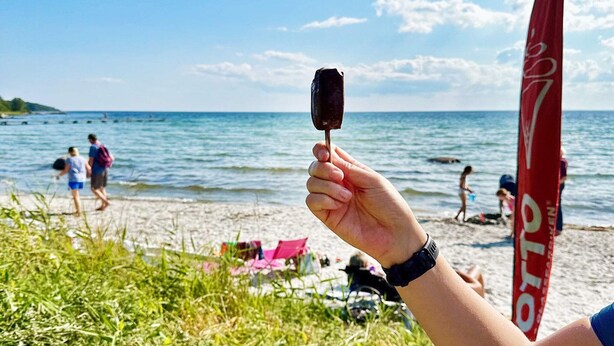 A person holding a chocolate ice cream bar at a beach with a clear sky and ocean in the background. - 4 Star Holiday Home in Solvesborg-by Traum (Sölvesborg)
