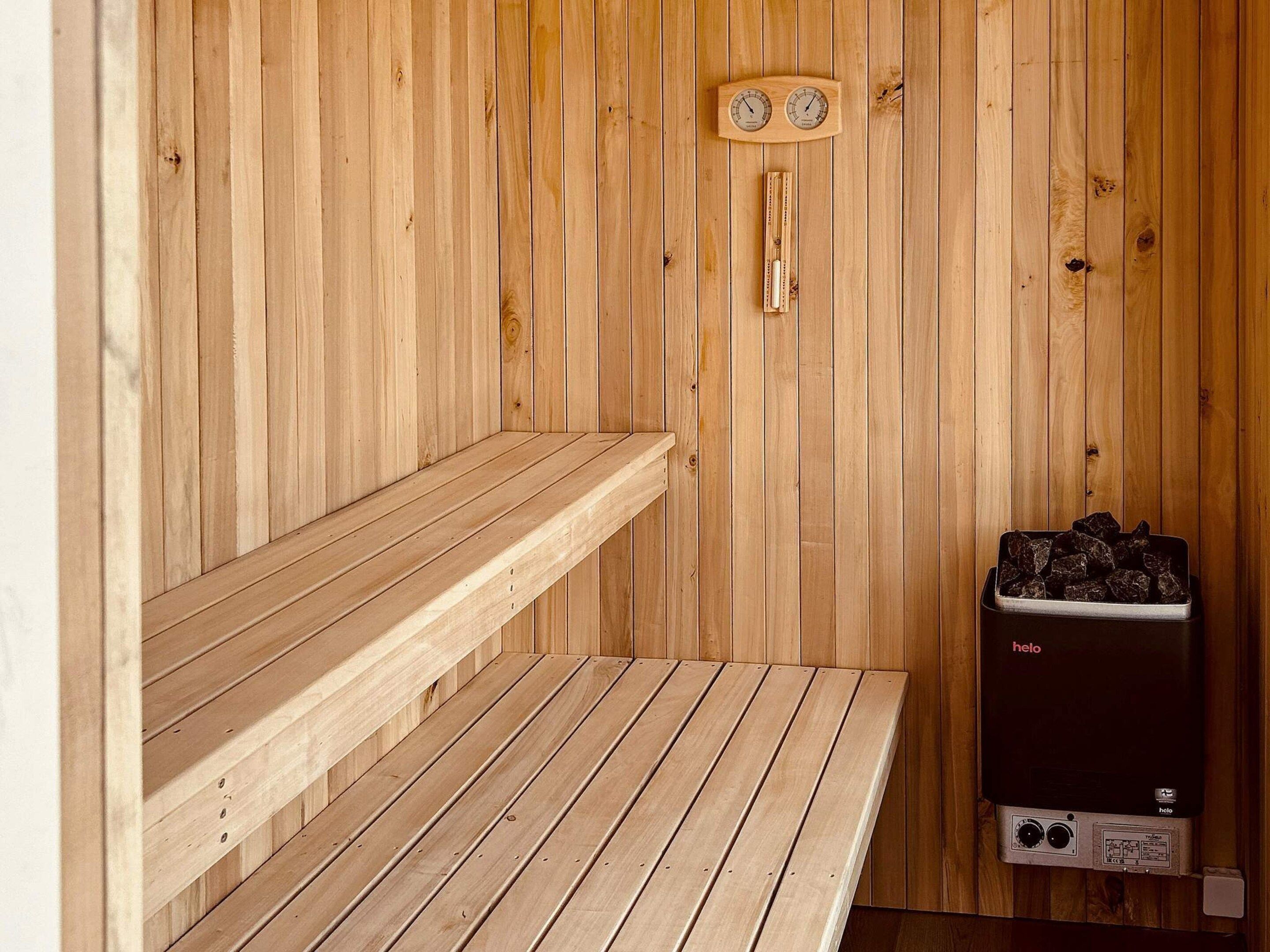 Een sauna met houten banken en een verwarming met de tekst 'helo'.