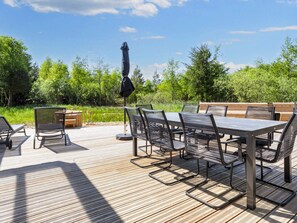 An outdoor deck with a table and chairs, surrounded by greenery. - 5 Star Holiday Home in Oster Assels (Øster Assels)