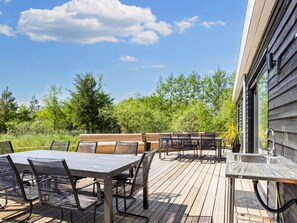 An outdoor deck with a table and chairs, a bench, and a sink. - 5 Star Holiday Home in Oster Assels (Øster Assels)