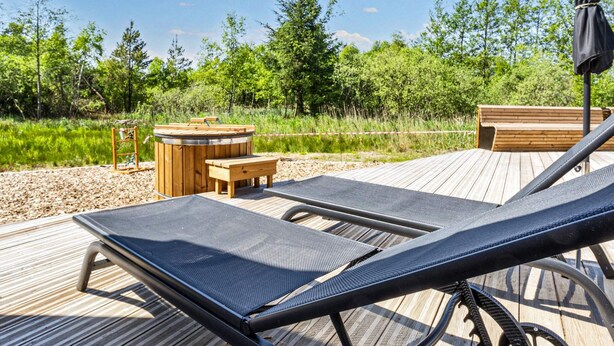 A wooden deck with lounge chairs, a small table, and a hot tub. - 5 Star Holiday Home in Oster Assels (Øster Assels)