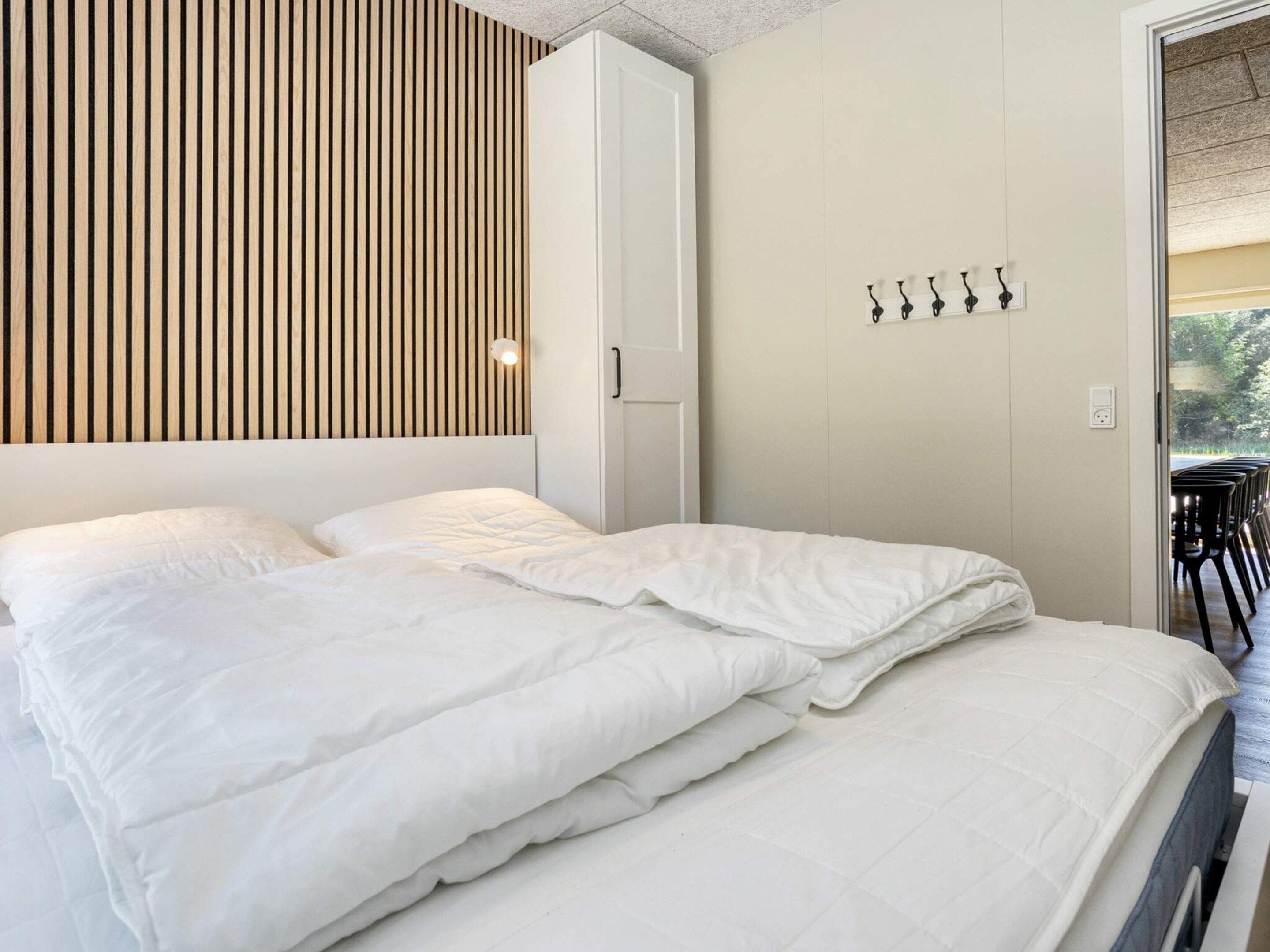 A bedroom with a bed, a wardrobe, and a wall-mounted light fixture.