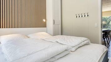 Een slaapkamer met een bed, een kledingkast en een wandlamp.