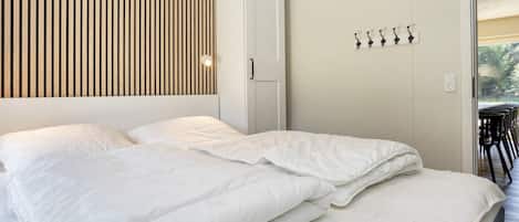 A bedroom with a bed, a wardrobe, and a wall-mounted light fixture.