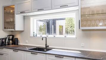 A modern kitchen with white cabinetry, a black countertop, and a window with a view of greenery.